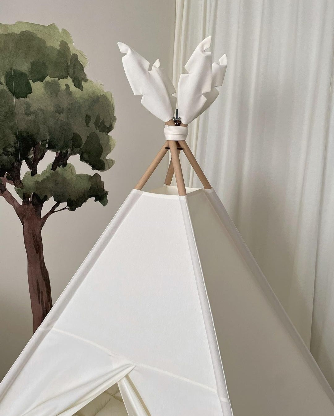 Krov dečijeg šatora za sobu krem boje sa indijanskim motivima koji budi maštu svakog mališana.Dečiji šator za sobu iza njega je oslikano drvo sa braon stablom i zelenim listovima.